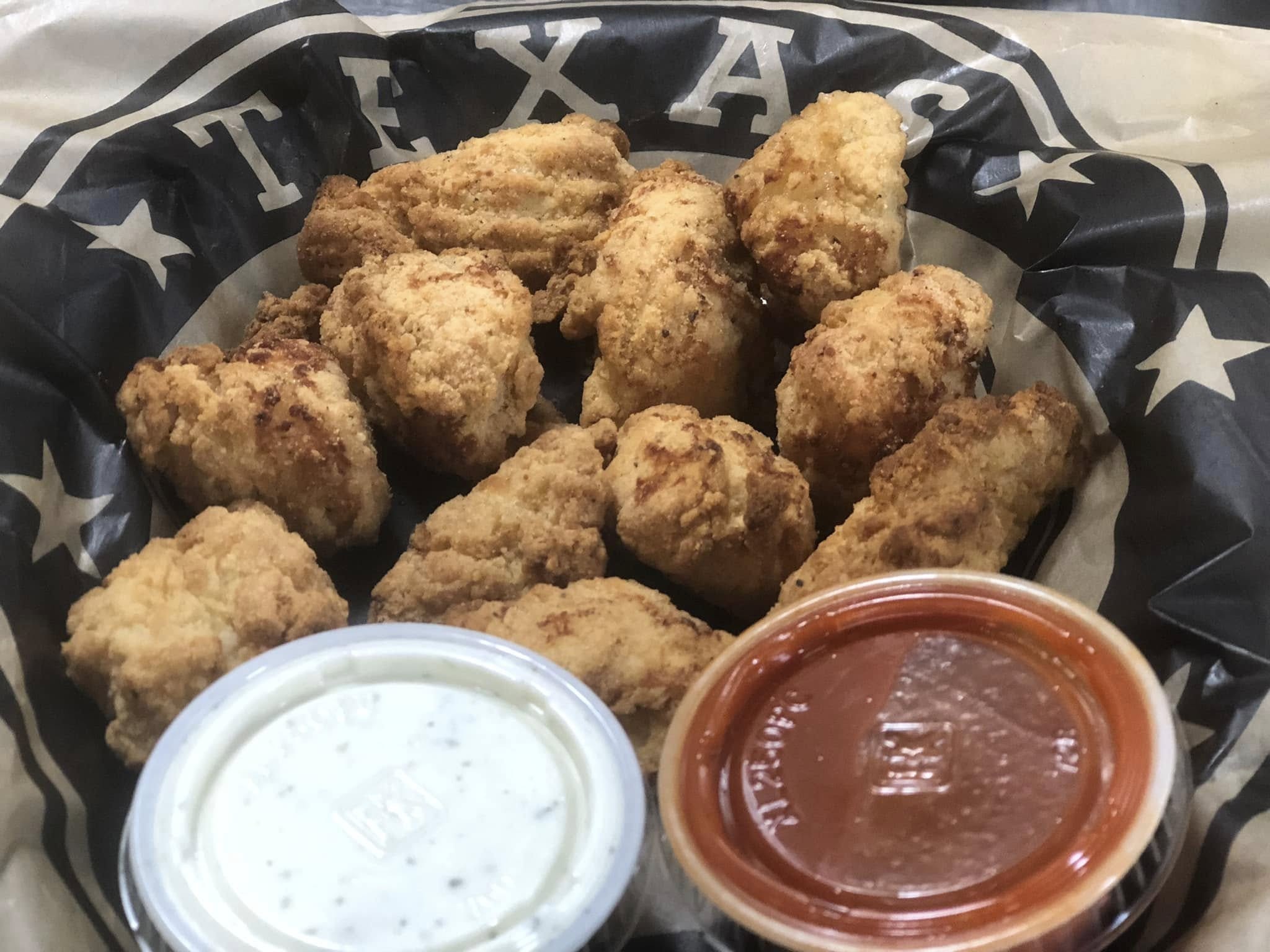 A basket of crispy fried chicken wings on TEXAS-printed paper, served with ranch and buffalo sauce—perfect for sharing at Studebakers Pizza & Tap Wall Gatesville TX.