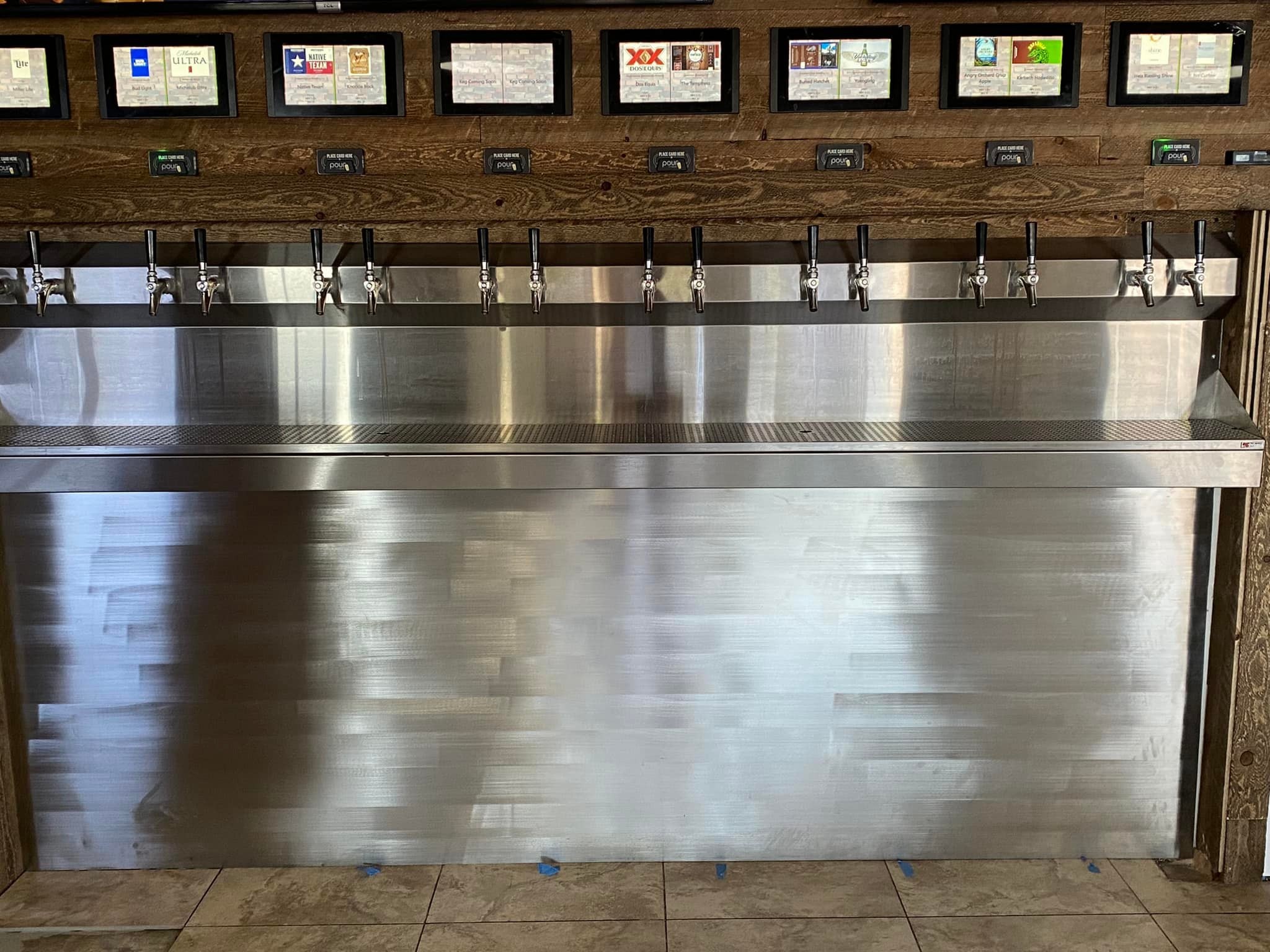 A row of beer taps lines the stainless steel counter at Studebakers Pizza & Tap Wall Gatesville TX, beneath digital screens showing beverage options in this self-serve bar. The area is clean and organized, reflecting a top Gatesville restaurant experience.