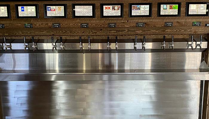 A row of beer taps below the Studebakers Menu Gatesville TX, mounted on a wooden wall in a bar or brewery setting.